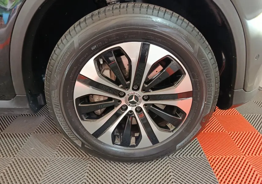Gros plan sur la roue avant gauche du Mercedes GLC 300 e Business Line noir avec jante alliage bicolore.