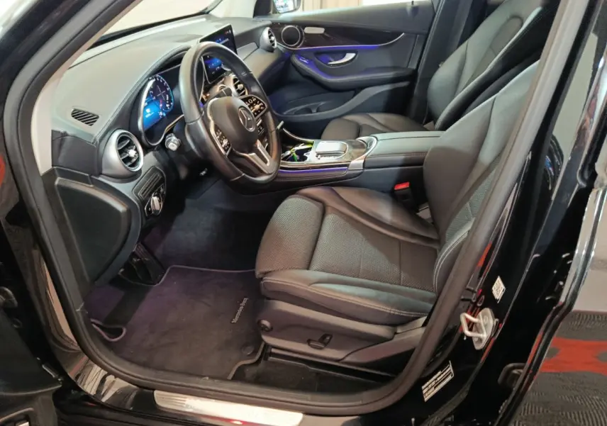 Intérieur côté conducteur d'une Mercedes GLC 300 e Business Line noire, avec tableau de bord digital et sièges cuir noirs.
