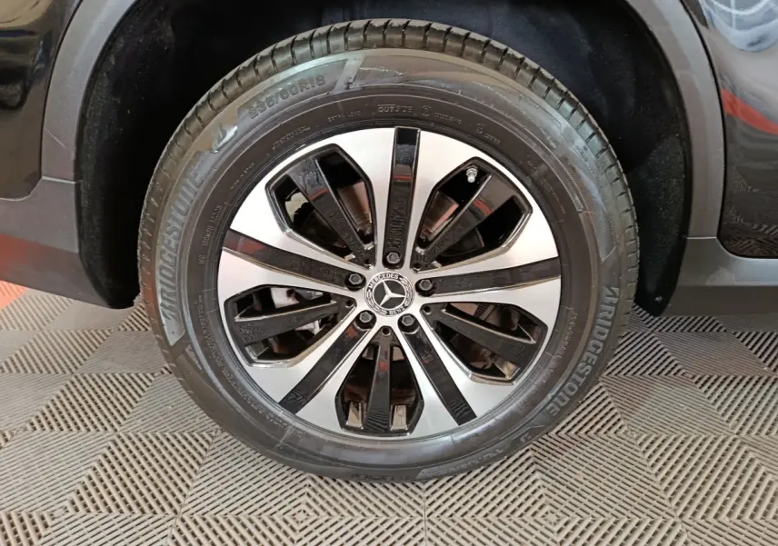 Gros plan sur la roue avant droite d’un Mercedes GLC 300 e noir avec jante alliage bicolore et pneu Bridgestone.