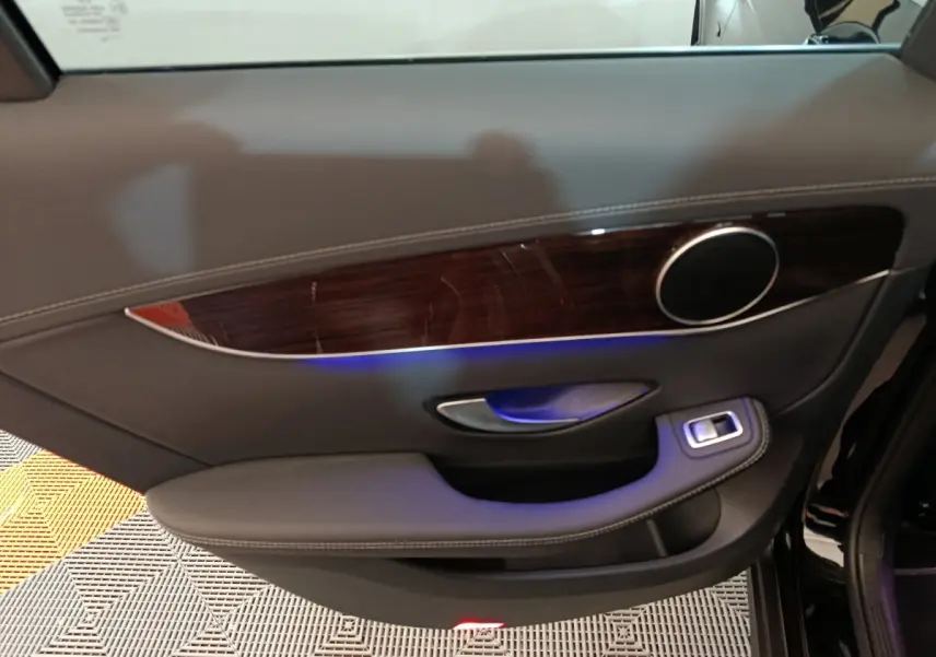 Panneau de porte côté gauche noir avec insert bois et éclairage d'ambiance bleu dans une Mercedes GLC 300 e 2020.