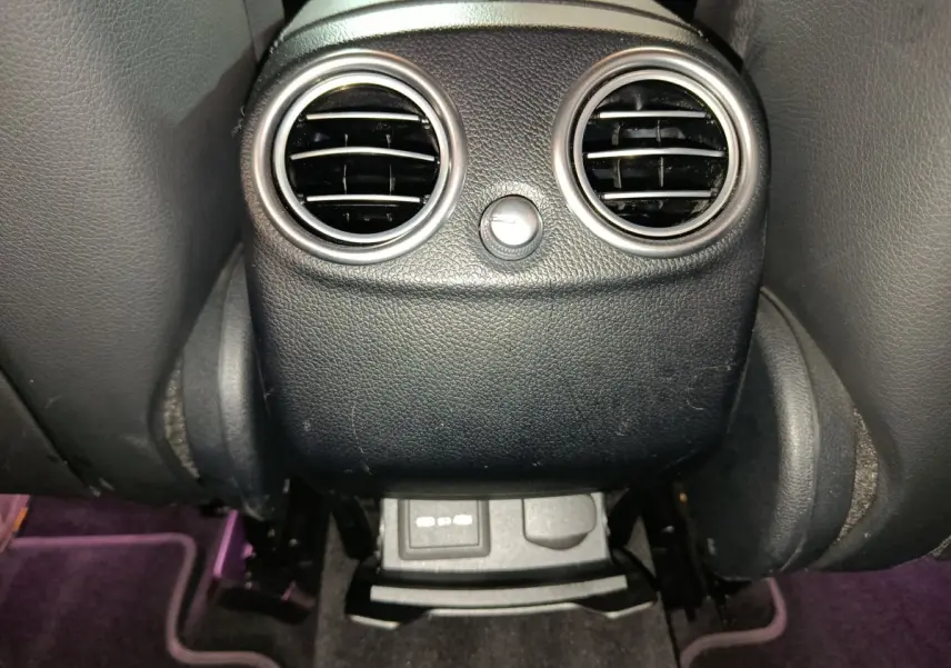 Gros plan sur la console arrière noire du Mercedes GLC 300 e Business Line 2020 avec bouches d’aération rondes et prises USB.