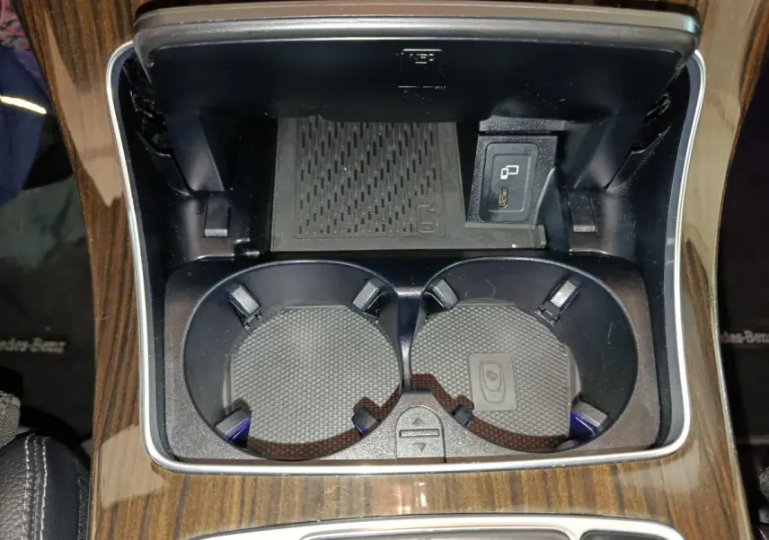 Gros plan sur les porte-gobelets et prise USB du coffre central en bois foncé d'un Mercedes GLC 300 e noir.