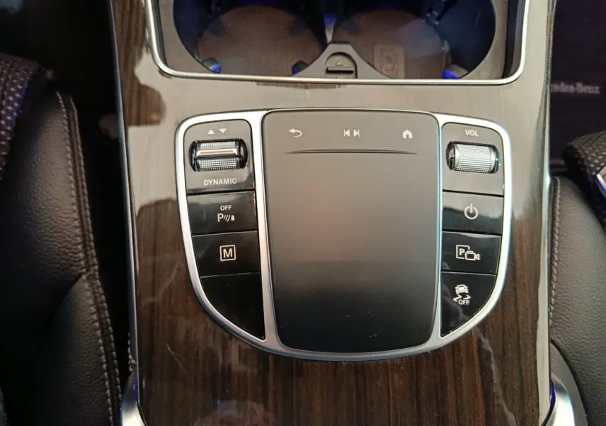 Gros plan sur la console centrale en bois avec pavé tactile et commandes du Mercedes GLC 300 e Business Line noir.