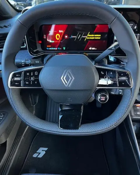 Vue centrée sur le volant noir de la Renault R5 électrique 2024 avec tableau de bord numérique et logo Renault visible.