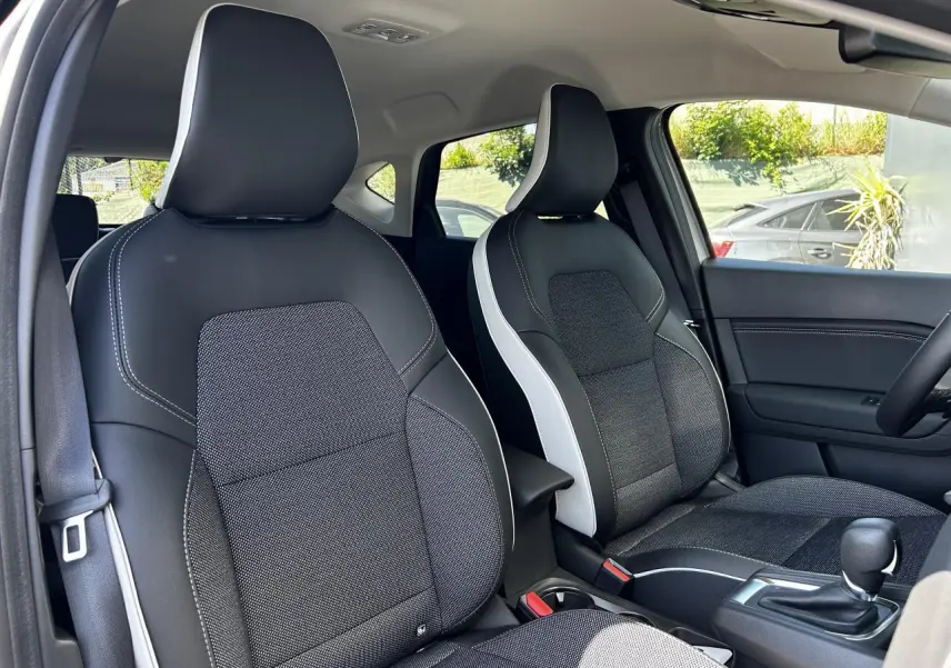 Vue intérieure avant du Renault Captur 2024, sièges bi-matière noirs et gris avec surpiqûres blanches.
