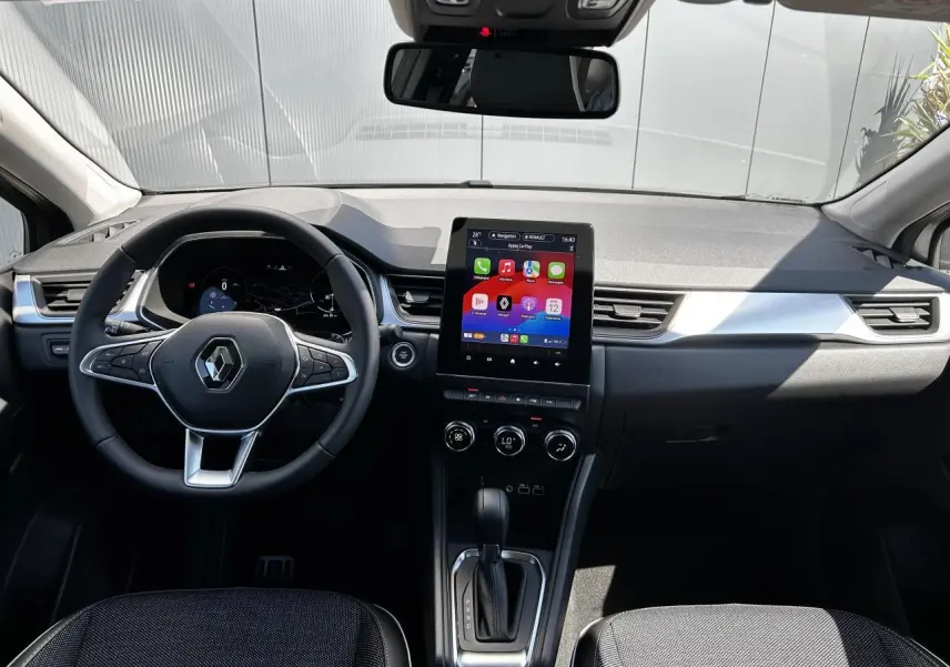 Vue intérieure frontale du tableau de bord du Renault Captur 2024 avec écran tactile vertical et volant multifonction.