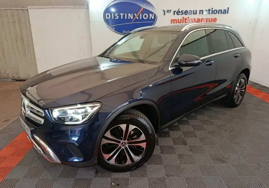 Mercedes GLC hybride rechargeable bleu en 3/4 avant droit, avec jantes alliage et phares LED allumés.