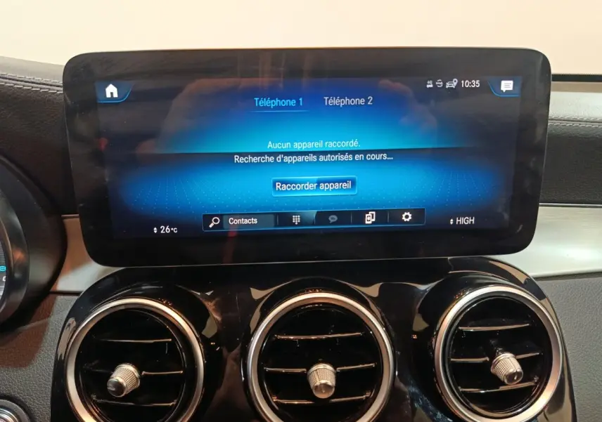 Écran tactile central et trois aérateurs ronds chromés du tableau de bord du Mercedes GLC 300 E bleu.