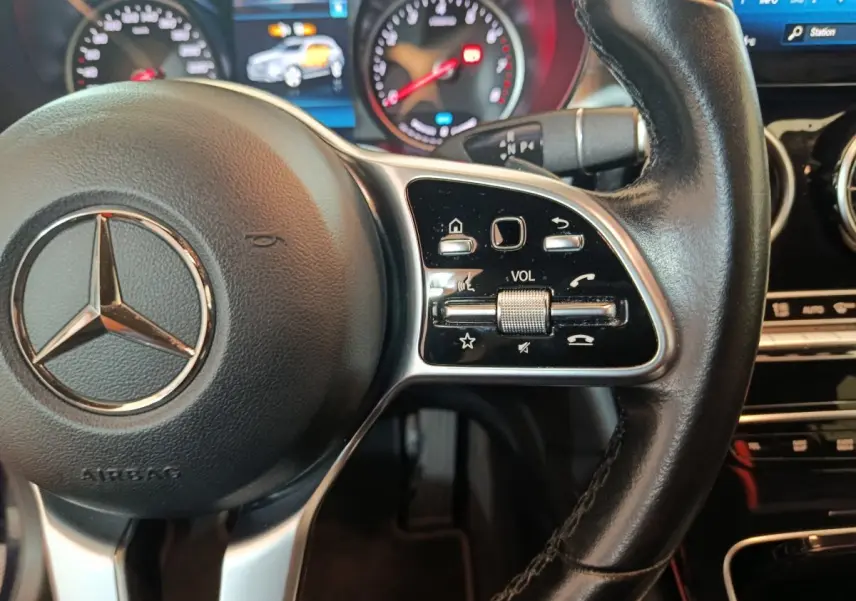 Gros plan sur le volant cuir noir de la Mercedes GLC 300 E Business Line 2021 avec commandes audio et tableau de bord lumineux.
