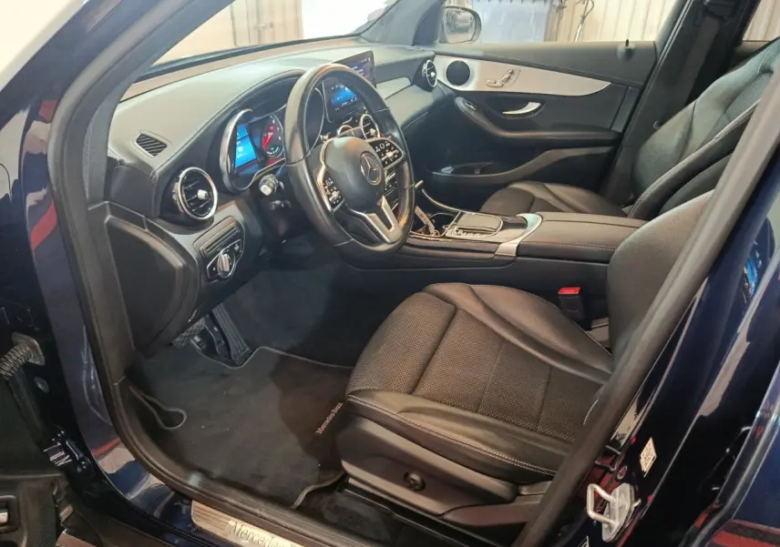 Vue intérieure côté conducteur du Mercedes GLC 300 E Business Line 2021 bleu, avec tableau de bord digital et sièges cuir noirs.