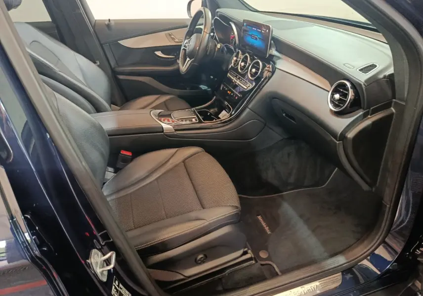 Intérieur avant droit d'un Mercedes GLC bleu 2021, sièges cuir noirs et tableau de bord avec écran tactile.