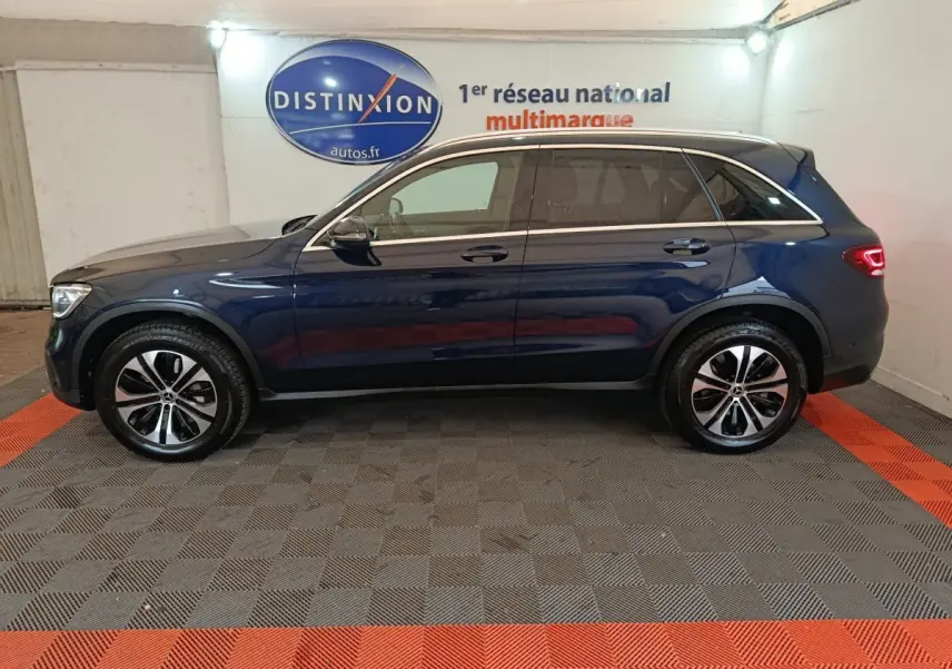 Profil côté gauche d'un Mercedes GLC 300 E Business Line 4MATIC bleu, avec jantes alliage et feux arrière allumés.