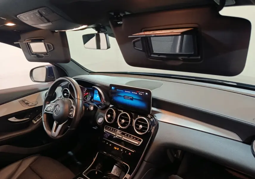Vue intérieure côté conducteur du tableau de bord noir et beige du Mercedes GLC 300 E Business Line 2021 avec écran tactile central.