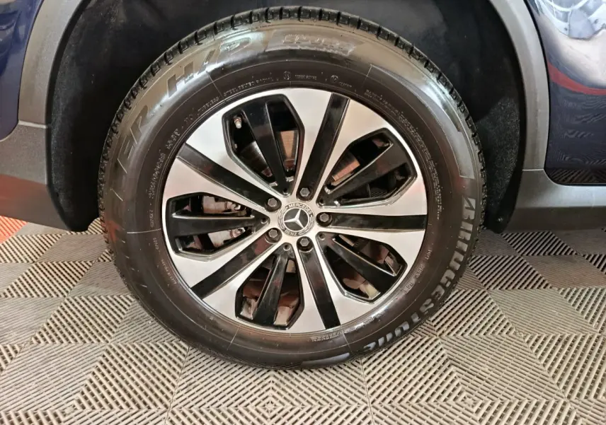 Gros plan sur la roue avant droite du Mercedes GLC 300 E Business Line bleu, jante alliage bicolore et pneu Bridgestone.
