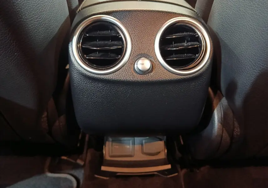 Vue rapprochée des aérateurs arrière noirs avec cerclages argentés dans l’habitacle du Mercedes GLC 300 E bleu 2021.