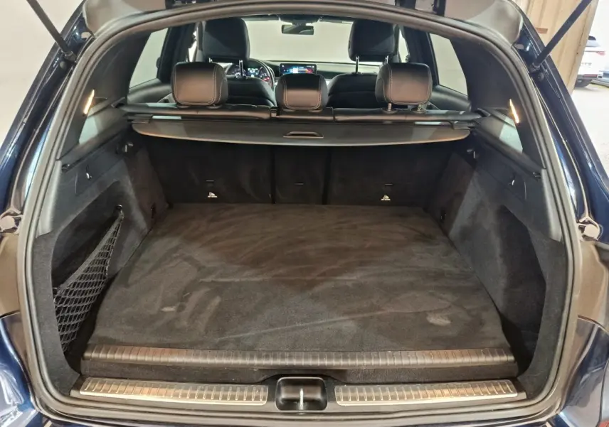 Coffre ouvert vu de l'arrière du Mercedes GLC 300 E Business Line bleu, avec cache-bagages et sièges noirs visibles.