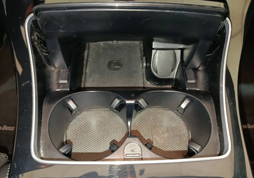 Gros plan sur les porte-gobelets noirs et prise 12V dans la console centrale du Mercedes GLC 300 E bleu 2021.