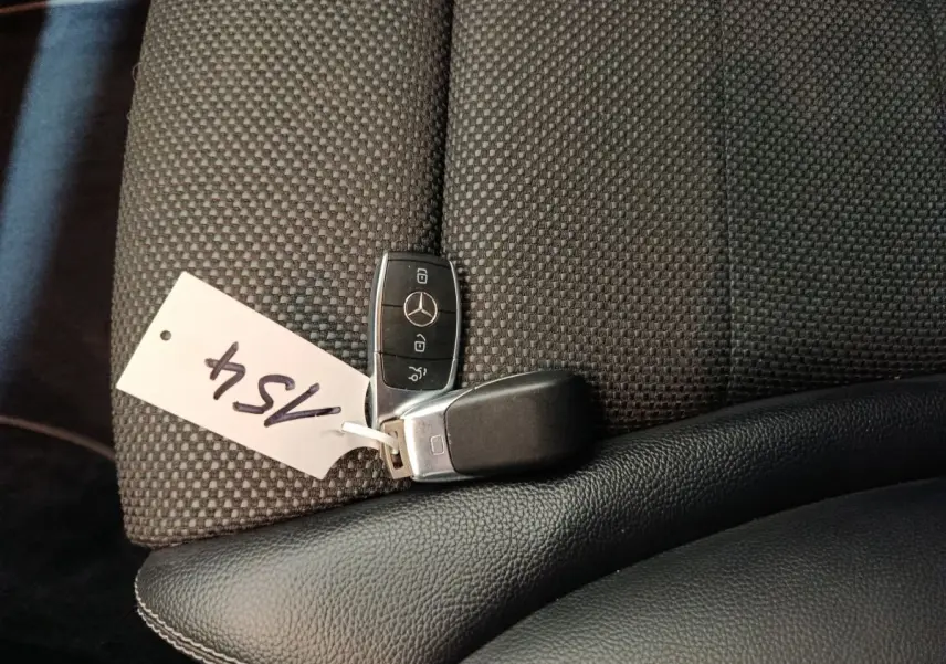 Clé Mercedes posée sur un siège tissu gris foncé avec cuir noir, intérieur d'une GLC hybride rechargeable 2021.