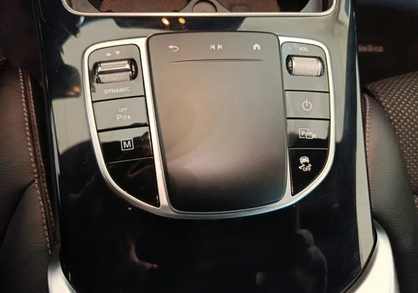 Gros plan sur la console centrale noire brillante du Mercedes GLC 300 E Business Line avec commandes tactiles et roulettes.