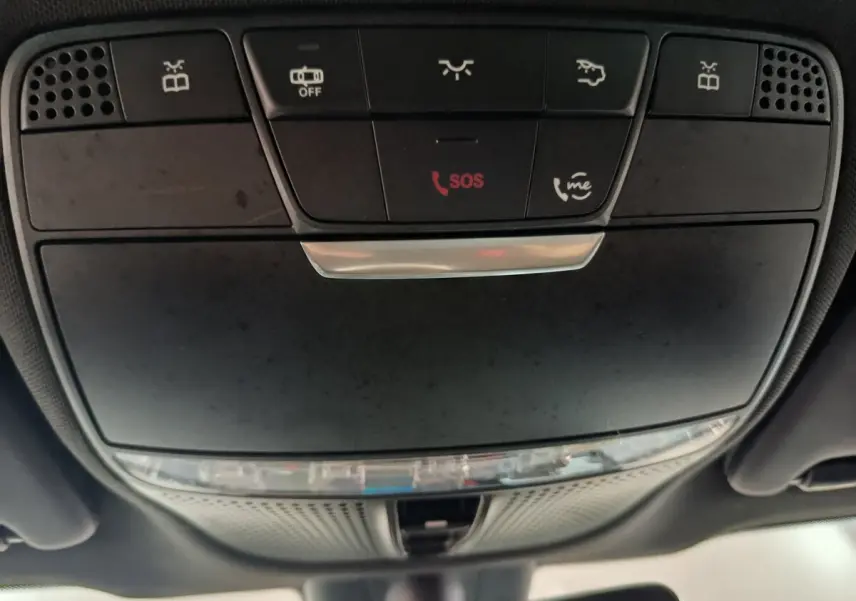 Vue en contre-plongée du panneau de commandes plafond noir du Mercedes GLC 300 E Business Line 2021 avec bouton SOS rouge.