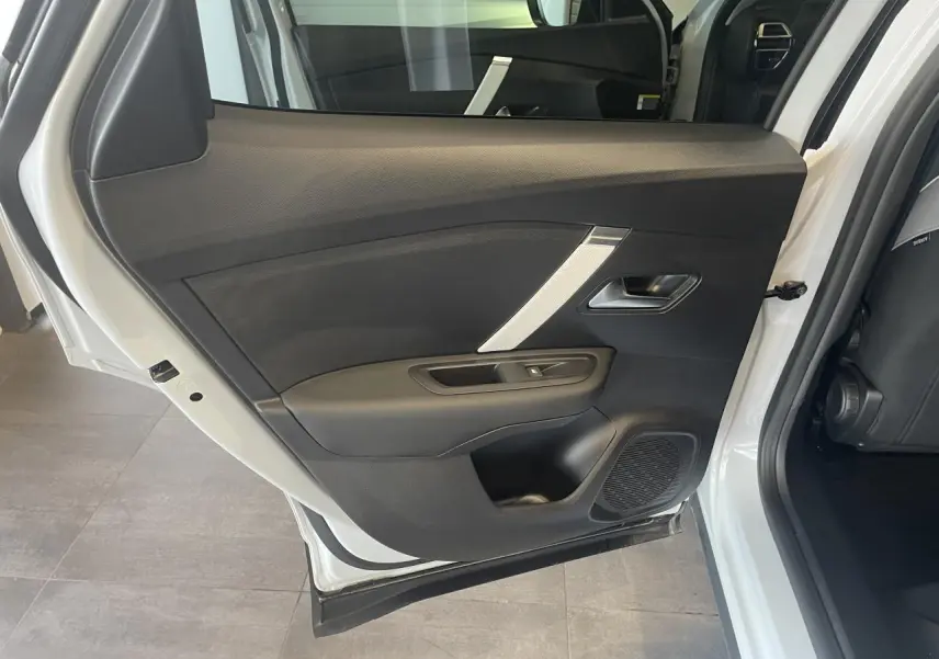 Vue intérieure de la porte arrière gauche d'une Citroën C4 blanche métallisée, avec garniture noire et insert argenté.