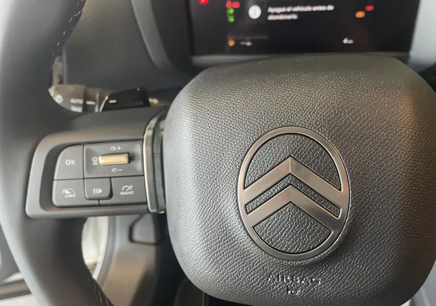 Gros plan sur le volant cuir noir de la Citroën C4 2025, avec commandes intégrées et logo chrome central.