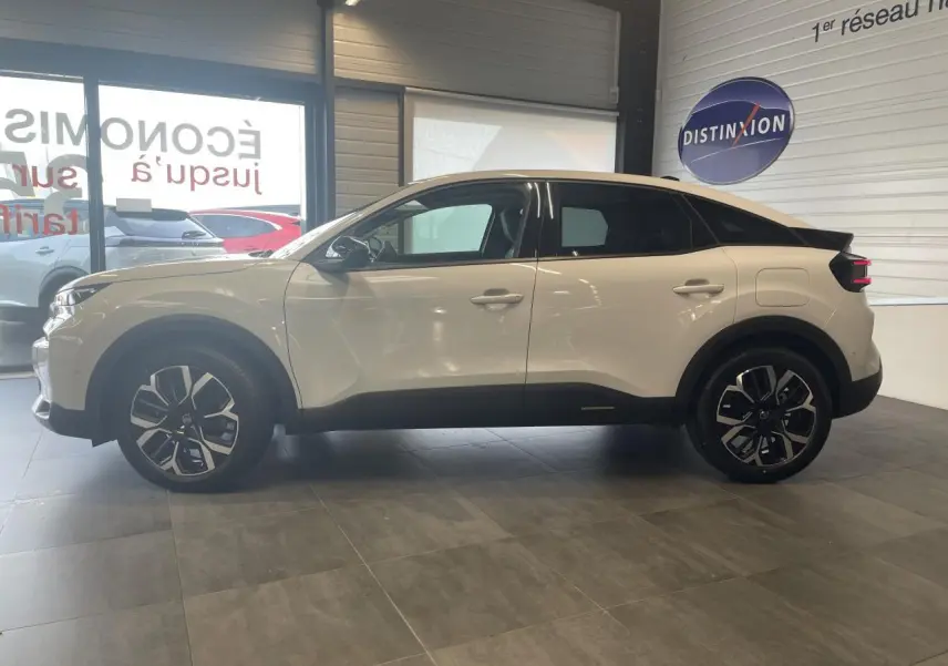 Profil droit d'une Citroën C4 blanche métallisée 2025 en showroom, avec jantes alliage et bas de caisse noirs.