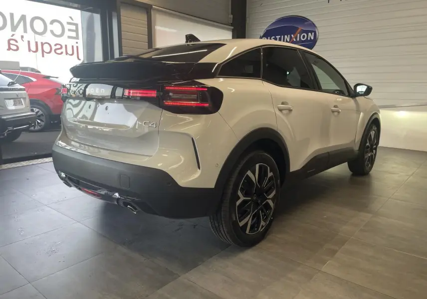 Vue 3/4 arrière droite d'une Citroën C4 blanche métallisée avec toit noir et jantes alliage 18 pouces.