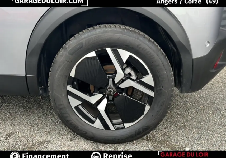 Gros plan sur la roue arrière droite d’un Peugeot 2008 Hybrid gris clair avec jante alliage noire et argentée.
