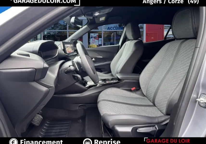 Vue intérieure côté conducteur du Peugeot 2008 Hybrid 136 e-DCS6 Allure 2025 avec sièges tissu gris clair et tableau de bord moderne.