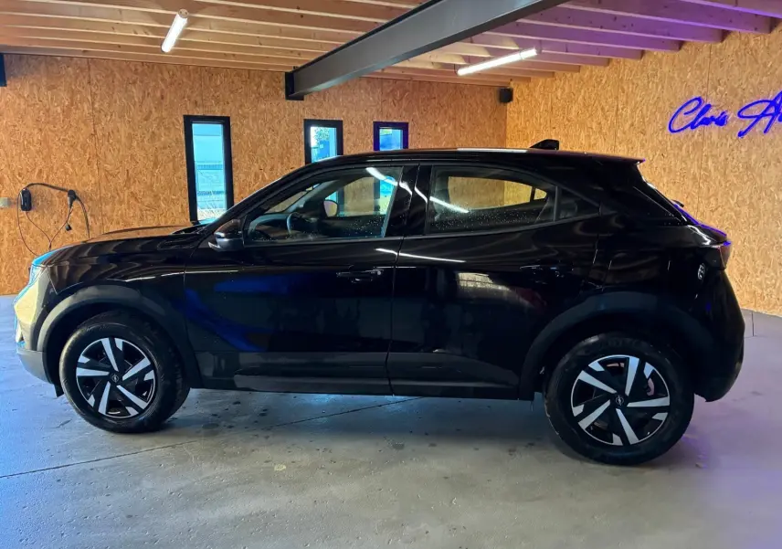 Vue latérale gauche d’un Opel Mokka 1.2 Turbo 145 Edition noir brillant, avec jantes distinctives et toit noir en intérieur bois.