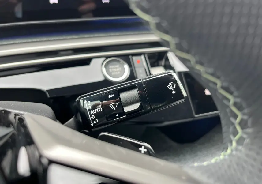 Gros plan sur la commande d'essuie-glace du Peugeot 3008 gris titane, avec volant partiellement visible en cuir noir.