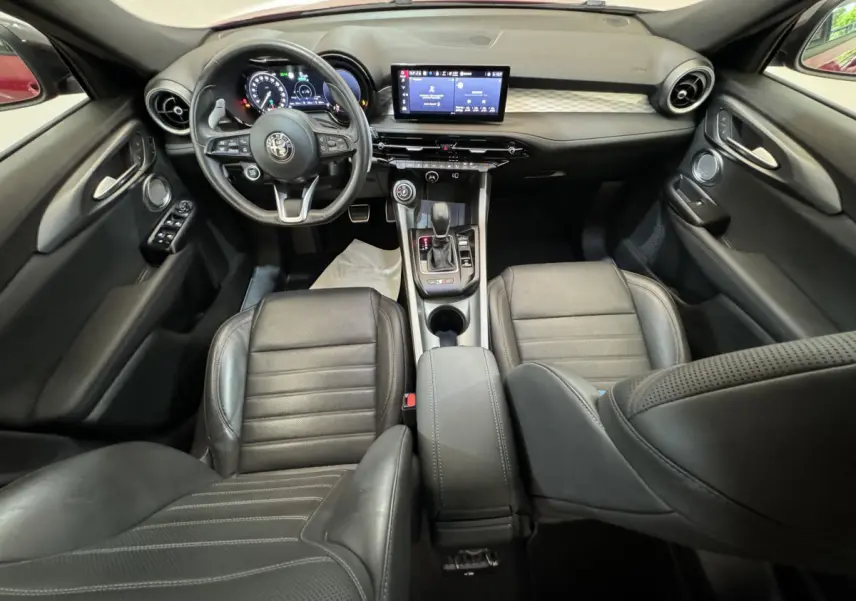 Intérieur noir cuir de l'Alfa Romeo Tonale 2023, vue de face sur tableau de bord et console centrale moderne.