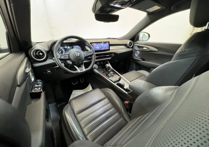 Intérieur noir de l'Alfa Romeo Tonale 2023 vu côté conducteur, avec tableau de bord digital et écran tactile central.