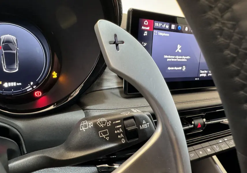 Gros plan intérieur sur la palette de changement de vitesse côté droit et l'écran tactile du tableau de bord de l'Alfa Romeo Tonale rouge.