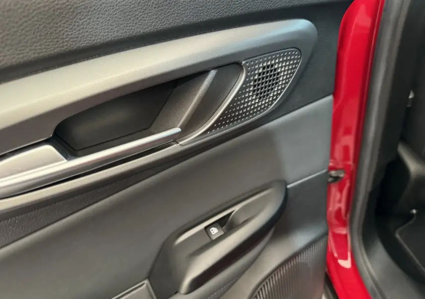 Gros plan sur la porte intérieure côté gauche de l'Alfa Romeo Tonale rouge, avec poignée alu et commande de vitre.