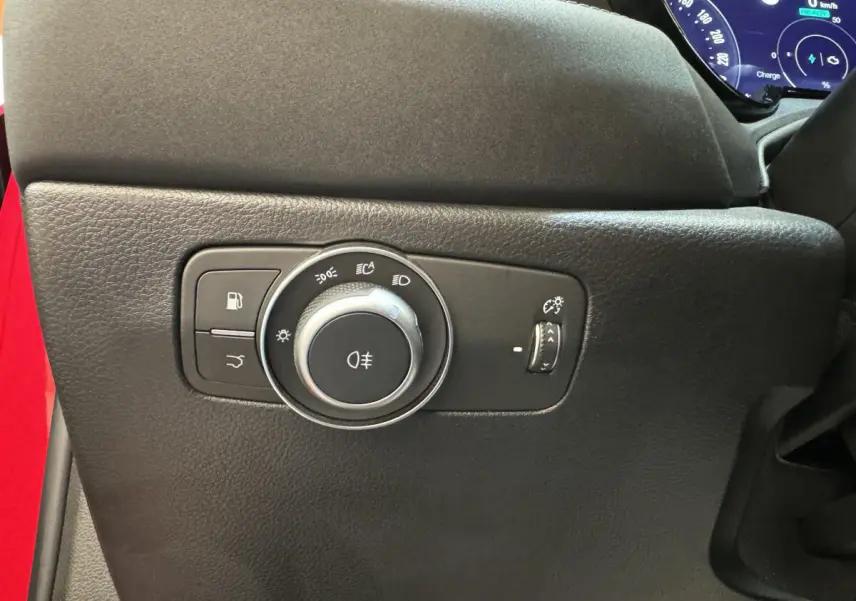 Gros plan sur la commande des phares et éclairage intérieur noir dans l'Alfa Romeo Tonale rouge, côté gauche du tableau de bord.