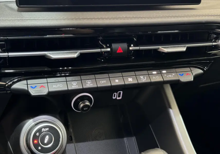 Vue rapprochée du tableau de bord noir de l'Alfa Romeo Tonale rouge, montrant les commandes climatisation et la molette de sélection.