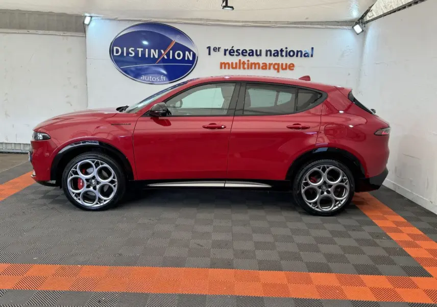 Profil côté gauche d'un Alfa Romeo Tonale rouge 2023 avec jantes distinctives en cercle et logo Distinxion en arrière-plan.