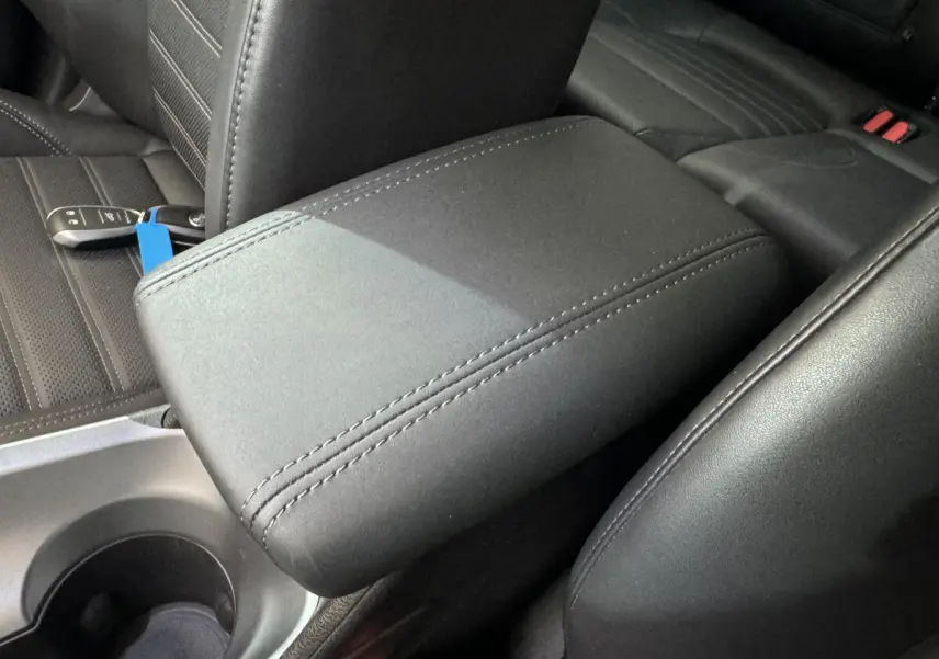 Accoudoir central en cuir noir avec coutures apparentes dans l'habitacle d'une Alfa Romeo Tonale rouge 2023.