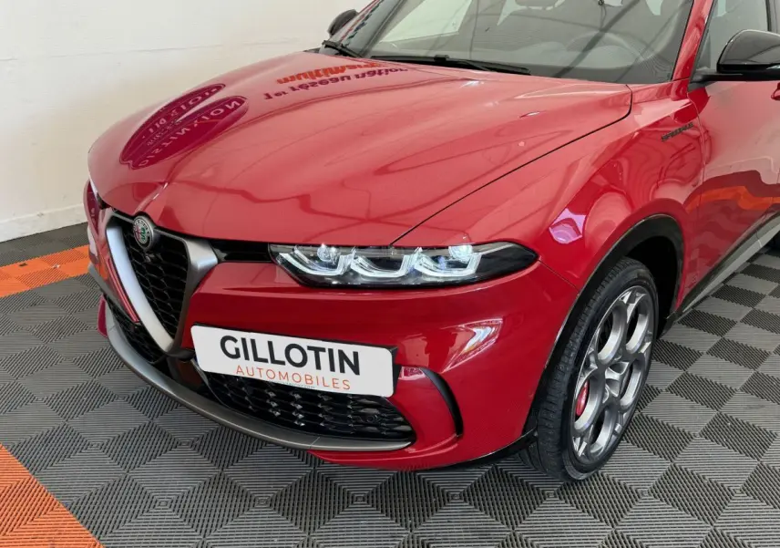 Vue 3/4 avant gauche d'une Alfa Romeo Tonale rouge avec calandre caractéristique et jantes spécifiques Edizione Speciale.