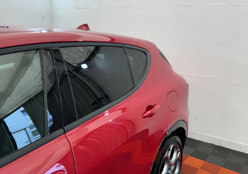 Vue côté arrière gauche de l'Alfa Romeo Tonale rouge 2023 avec jantes distinctives et vitres teintées.