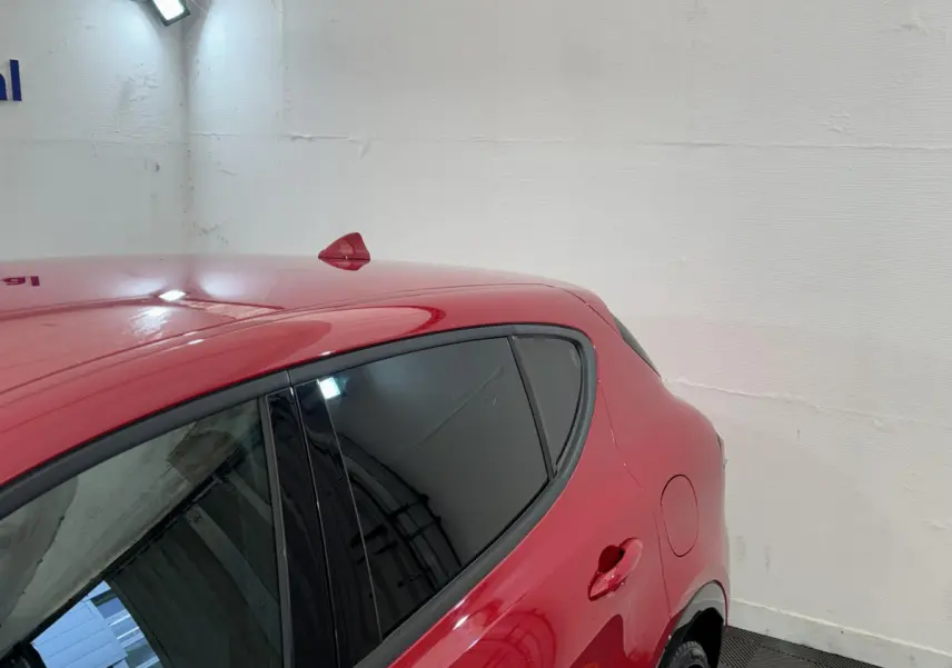 Vue côté droit arrière d'une Alfa Romeo Tonale rouge avec vitres teintées et antenne requin sur le toit