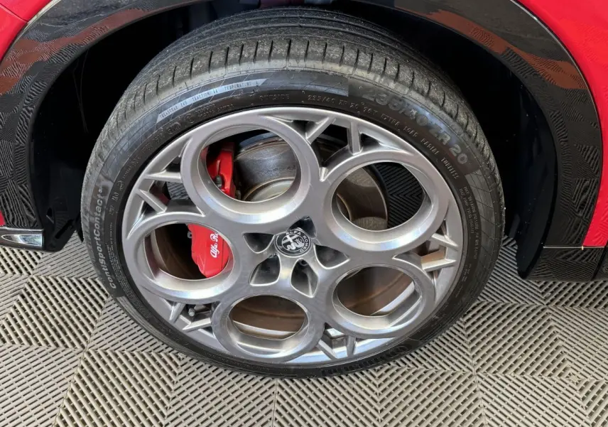 Gros plan sur la roue avant droite rouge d'une Alfa Romeo Tonale 2023 avec étrier de frein rouge et jante alu distinctive.
