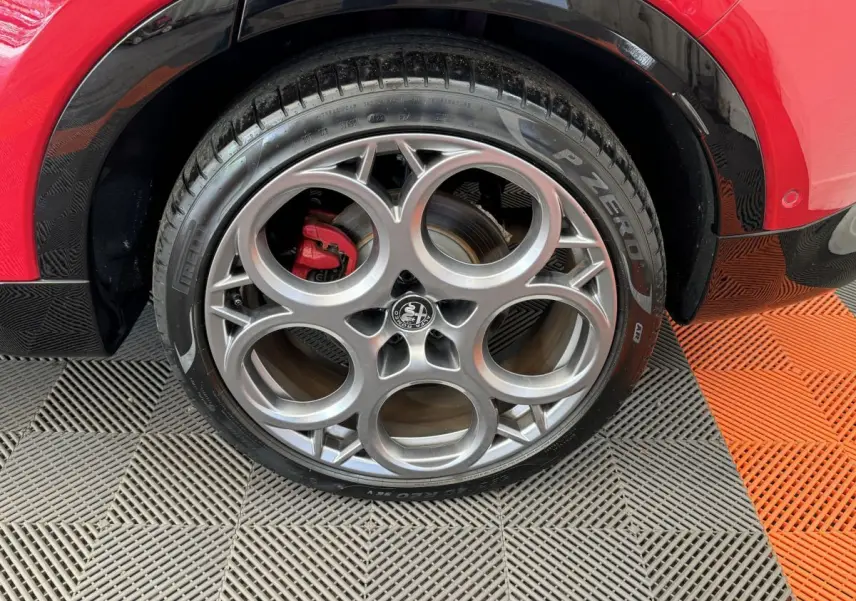 Gros plan sur la roue arrière droite de l'Alfa Romeo Tonale rouge, avec jante alliage et pneu Pirelli P Zero.