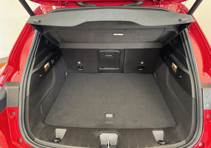 Coffre ouvert vu de l'arrière d'une Alfa Romeo Tonale rouge, montrant un espace de chargement propre et bien éclairé.