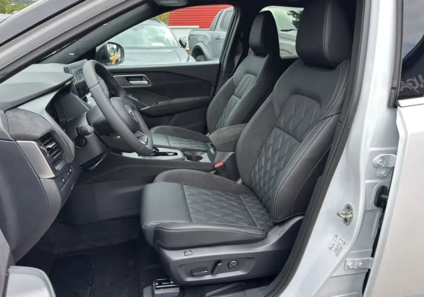 Vue intérieure côté conducteur du Nissan Qashqai E-POWER 205 Tekna Plus 2026, sièges cuir noirs avec surpiqûres grises.