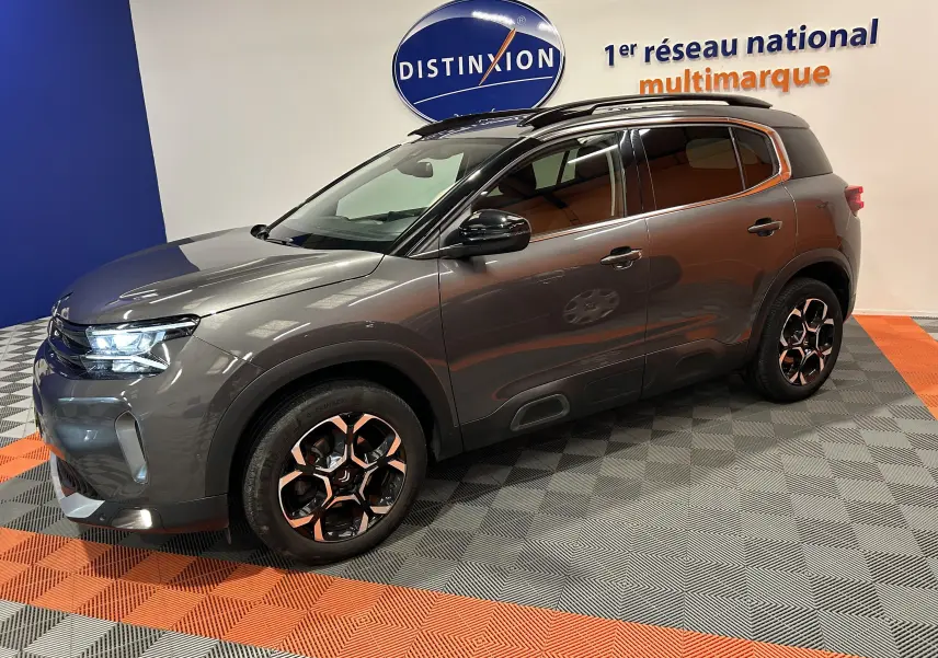 Citroën C5 Aircross gris Platinium en 3/4 avant droit, avec jantes bi-ton et toit noir en showroom.