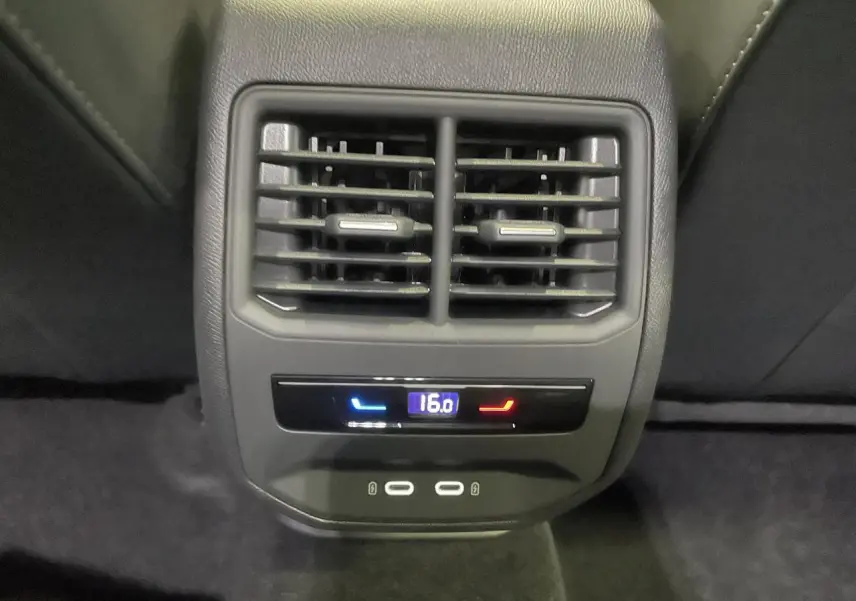 Gros plan sur la console arrière noire avec bouches d’aération, réglage climatisation à 16°C et deux ports USB-C.