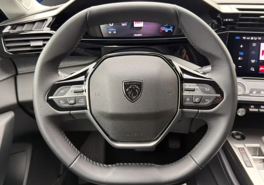 Vue rapprochée du volant cuir noir de la Peugeot 308 Hybrid 145 e-DCS6 Allure avec commandes multifonctions intégrées.